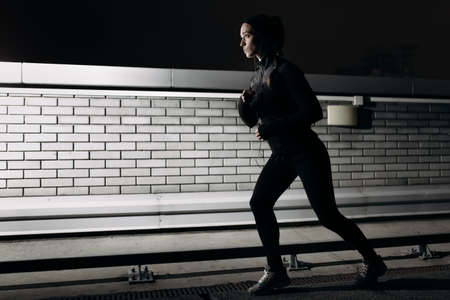 Woman running at nighttime on the parking roofの写真素材