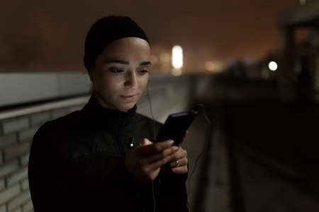 Woman using mobile phone on the parking roof at nightの写真素材