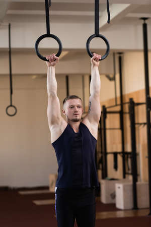 Caucasian athlete hanging on gymnastic rings