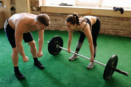 Trainer spotting a woman while she's exercising with weightの写真素材