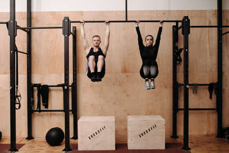 Man and woman doing exercise on horizontal barの写真素材
