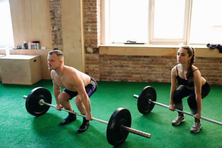 Two people lifting barbells during a gym workout