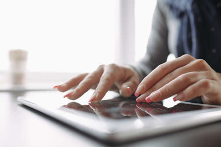 Cropped photo of woman hands using touchscreen tablet computerの写真素材