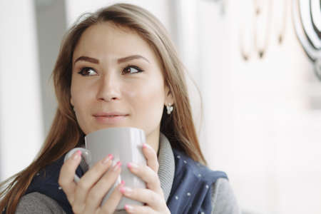 Attractive young woman sitting in a coffee shop at windowの写真素材