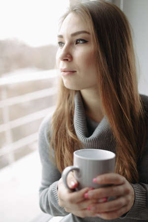 Attractive young woman sitting in a coffee shop at windowの写真素材