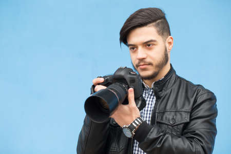 Male photographer photoshooting against a blue wall backgroundの写真素材