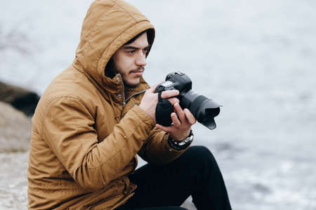 Photographer adjusts the camera at riverの写真素材