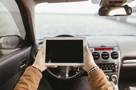 Man holding his digital tablet in car. First-person view.