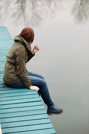 Young woman sitting on a pier at the river
