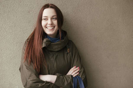 Woman in stylish coat standing at wall background and smile