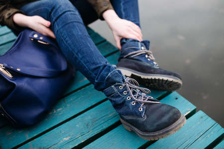 Woman sitting on pier at the river in a cold cloudy day. Cropped photo.の写真素材