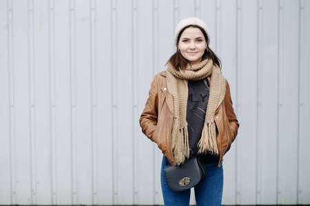 Young beautiful girl in a leather jacket standing at wall backgroundの写真素材