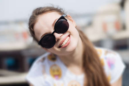 Happy smiling girl in sunglasses. Woman on the city waterfront.の写真素材