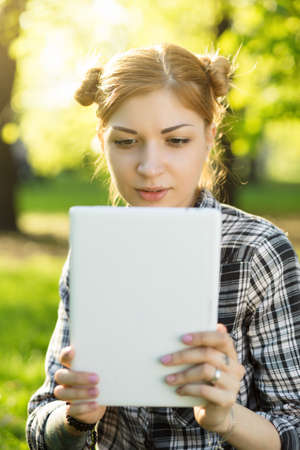 Young woman take a photo using tablet in the parkの写真素材