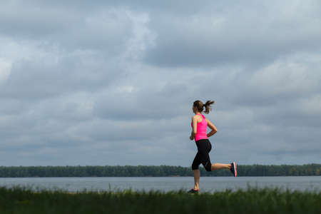 Young sporty woman running at quayの写真素材