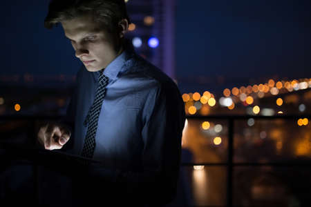 Businessman using his digital tablet late at night