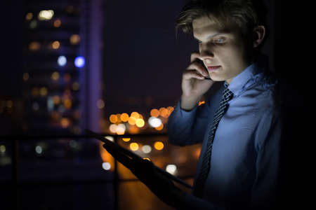 Businessman talking on his cellphone late at nightの写真素材