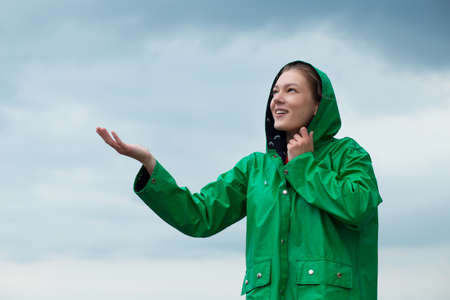 Woman in raincoat at overcast sky backgroundの写真素材