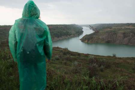 People in raincoat looking at flooded quarry landscapeの写真素材