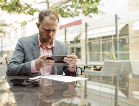 Businessman sitting at outdoor cafe and take picture of documentの写真素材