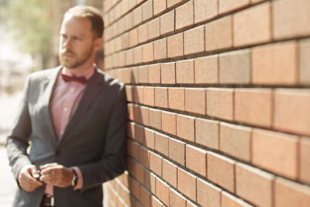 Portrait of handsome adult businessman near brick wallの写真素材