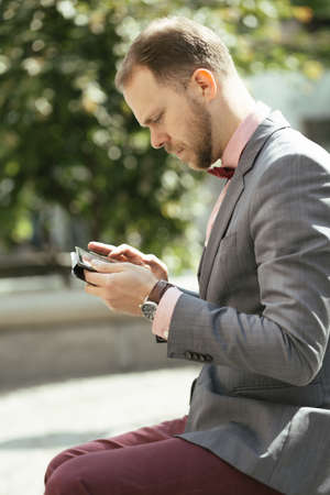 Businessman using digital tablet sitting on bench in a parkの写真素材