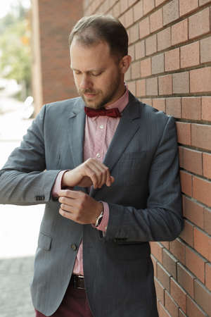 Portrait of handsome adult businessman near brick wall