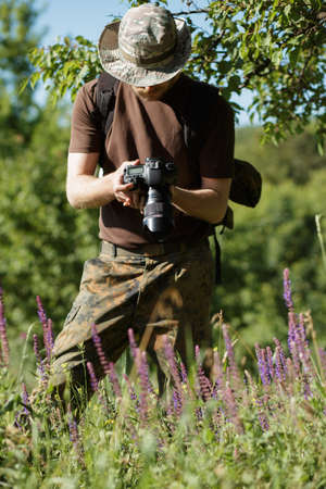 Photographer shooting flowers with DSLR camera in forestの写真素材