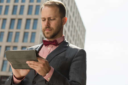 Businessman using digital tablet at high building backgroundの写真素材
