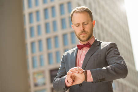 Handsome adult businessman looking on watch in downtownの写真素材