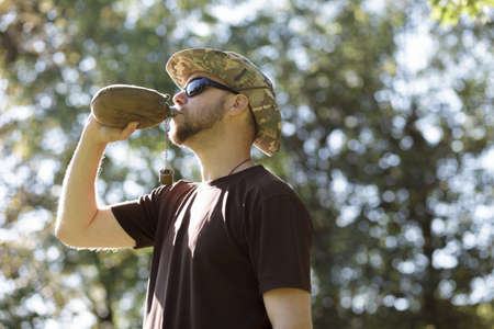 Hiking concept. Thirsty man having break drinking a flask of water.の写真素材