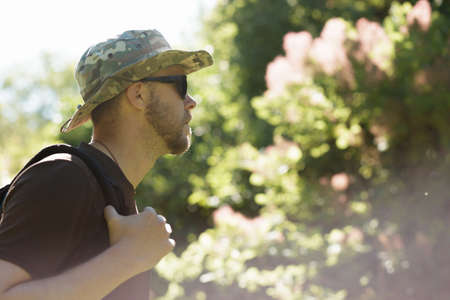 Male tourist in hat walking alone in forest. Cropped shot.の写真素材