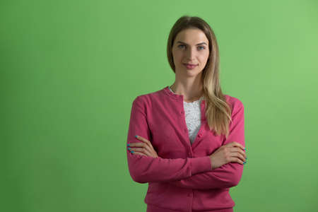Young cute woman standing with her arms folded, green backgroundの写真素材