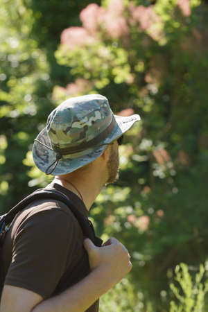 Male tourist in hat walking alone in forest. Cropped shot.の写真素材