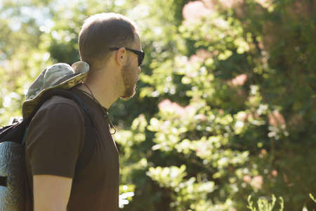 Male tourist in hat walking alone in forest. Cropped shot.の写真素材
