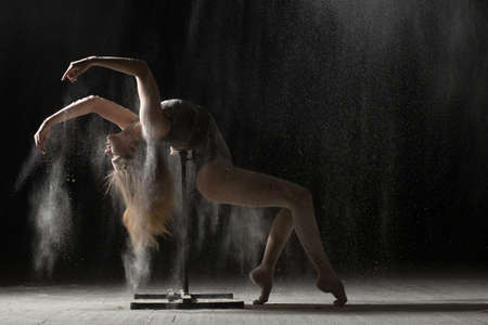 Woman doing gymnastic element on stand while sprinkled flourの写真素材