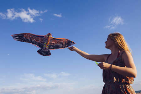 Woman hold flying kite in field at sky backgroundの写真素材