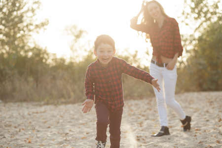 Joyful boy running to camera at nature, mother in a backgroundの写真素材