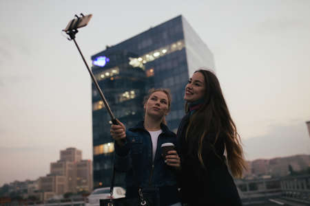 Outdoors portrait of two funny women friends make a selfie in cityの写真素材