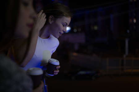 Two woman friends look down in balcony at nightの写真素材