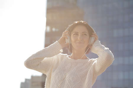 Woman listen music at building background, low contrast image