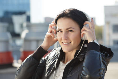 Woman with white earphones listen music in city