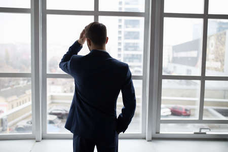 Businessman in white office thinking standing at window