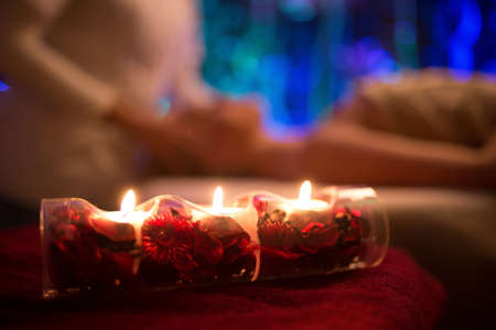 Spa lit candle and massage on backgroundの写真素材
