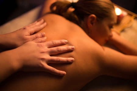 Masseur make spa procedure by candle light for womanの写真素材