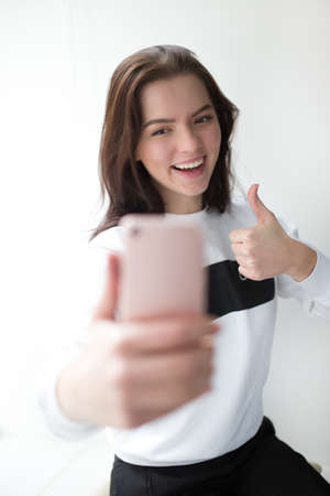 Woman in pullover make a selfie on white background
