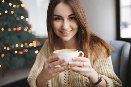 Lovely woman keep cup of coffee in a cafeの写真素材