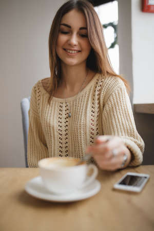 Woman stir sugar spoon in cup of cappuccino in cafeの写真素材