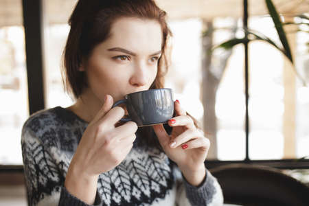 Woman drinking cappuccino in a coffee shop