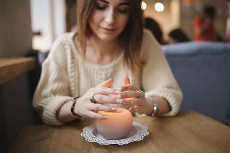 Woman warming hands above candleの写真素材